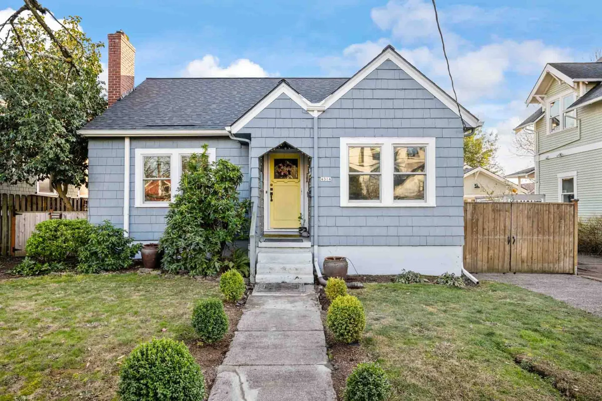 This exterior image displays the front of the home, featuring a cheerful bright yellow door, symmetrical windows, and neatly trimmed hedges. The inviting facade suggests a warm, private entry and hints at a peaceful domestic environment.