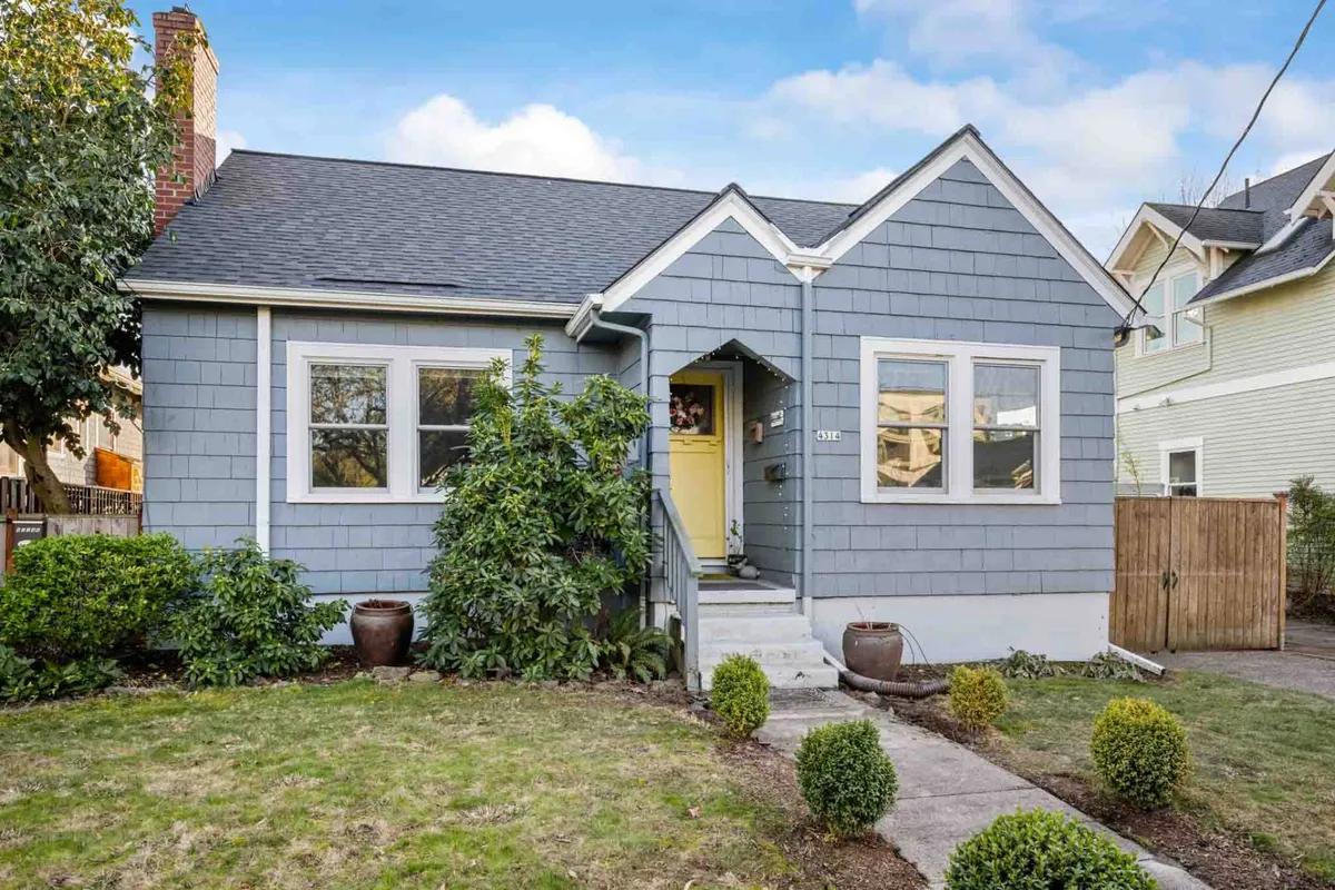 A cheerful exterior shot of a home featuring blue siding, a bright yellow front door, symmetrical windows, and a well-manicured front garden. The scene conveys a welcoming atmosphere with visible green space around the entrance, suggesting room for outdoor activities and family gatherings.
