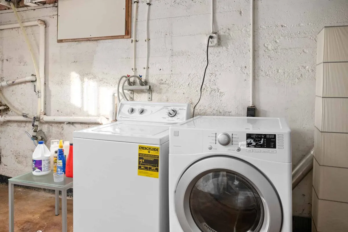 A practical, well-equipped laundry area with a modern washing machine and dryer, plus cleaning supplies neatly arranged. The space is clean and organized, underlining daily convenience for guests during their stay.